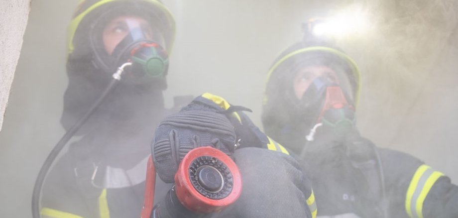 Einsatzkraft der Feuerwehr mit Atemschutzmaskeliegenden Baum